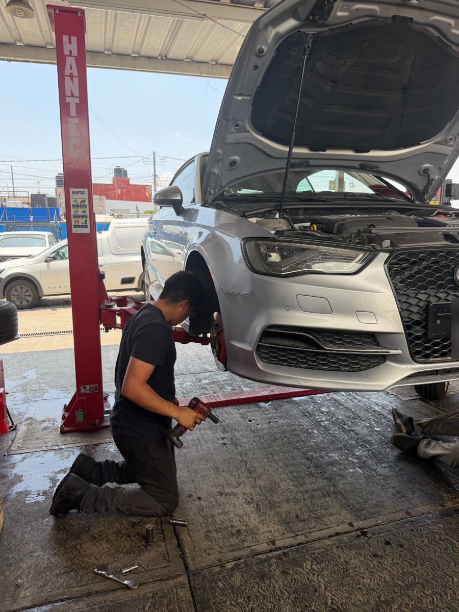 Mecánico trabajando en la suspensión de un auto en el elevador